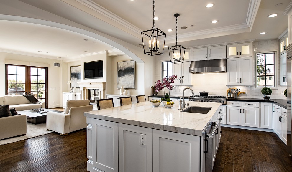 Large transitional l-shaped dark wood floor and brown floor eat-in kitchen photo in Orange County with an undermount sink, shaker cabinets, white cabinets, quartzite countertops, white backsplash, subway tile backsplash, stainless steel appliances, an island and white countertops