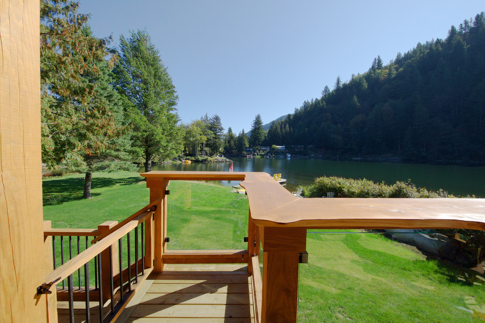 Photo of a mid-sized country backyard deck in Vancouver with a water feature and a roof extension.