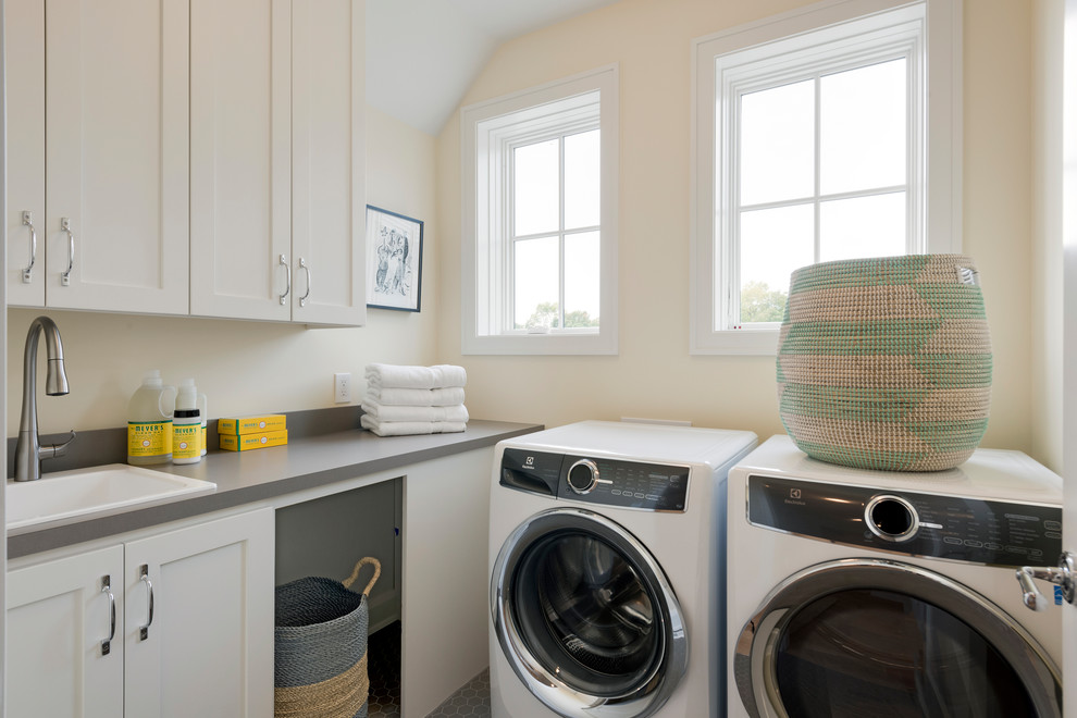 Mid-sized transitional dedicated laundry room in Minneapolis with a drop-in sink, shaker cabinets, white cabinets, a side-by-side washer and dryer, quartz benchtops, white walls, ceramic floors, grey floor and grey benchtop.