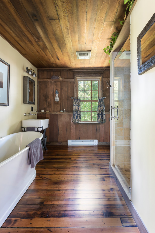 Idées déco pour une douche en alcôve montagne avec une baignoire indépendante, WC à poser, un mur beige, un sol en bois brun, une vasque et une cabine de douche à porte battante.