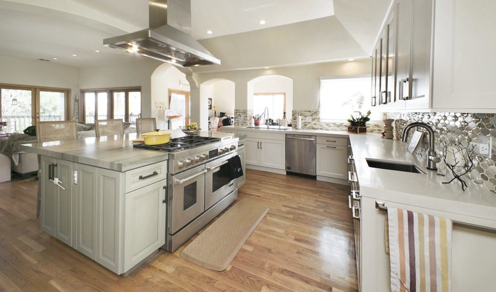 Inspiration for a large transitional u-shaped open plan kitchen in San Francisco with an undermount sink, recessed-panel cabinets, white cabinets, solid surface benchtops, multi-coloured splashback, mosaic tile splashback, stainless steel appliances, medium hardwood floors, with island, brown floor and white benchtop.