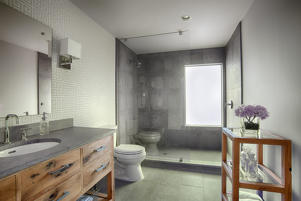 Mid-sized modern bathroom in Austin with an undermount sink, furniture-like cabinets, medium wood cabinets, concrete benchtops, an alcove shower, a one-piece toilet, gray tile, stone tile, grey walls and slate floors.