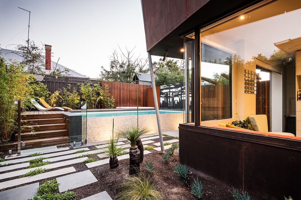 Photo of a mid-sized contemporary backyard full sun garden for summer in Melbourne with a garden path and natural stone pavers.