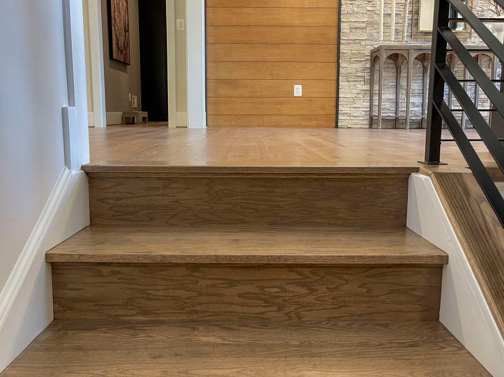 Ejemplo de escalera recta actual grande con escalones de madera, barandilla de varios materiales y panelado