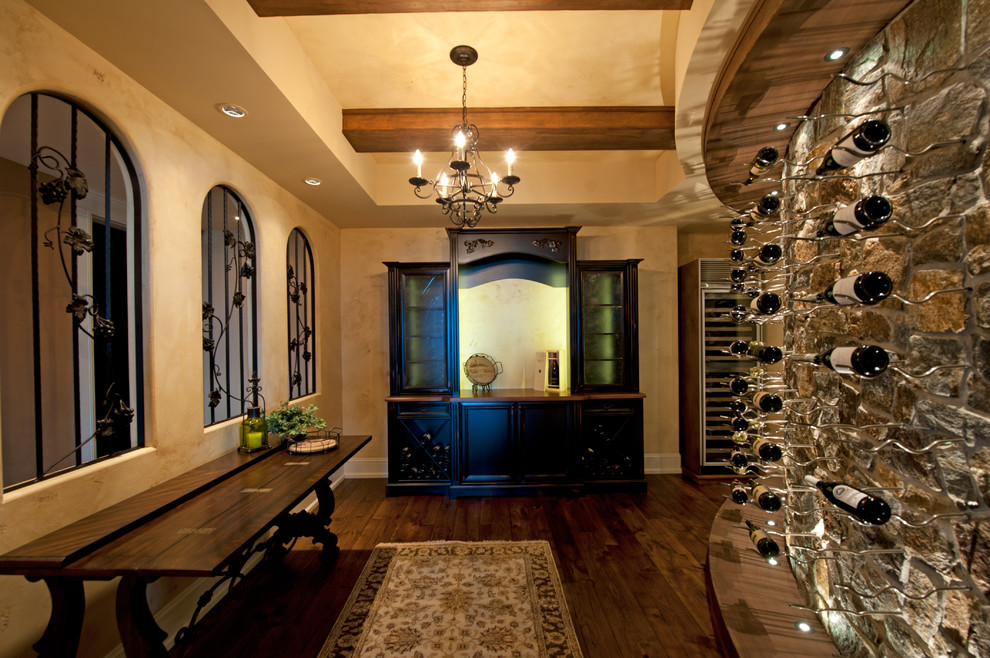 This is an example of a mediterranean wine cellar in Vancouver with dark hardwood floors, display racks and brown floor.