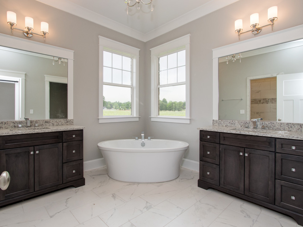 Photo of a large transitional master bathroom in Other with shaker cabinets, dark wood cabinets, a freestanding tub, white tile, grey walls, an undermount sink and marble benchtops.