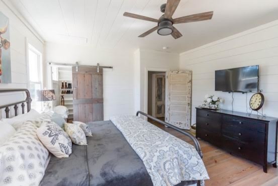 This is an example of a large country master bedroom in Austin with white walls, no fireplace, brown floor and light hardwood floors.