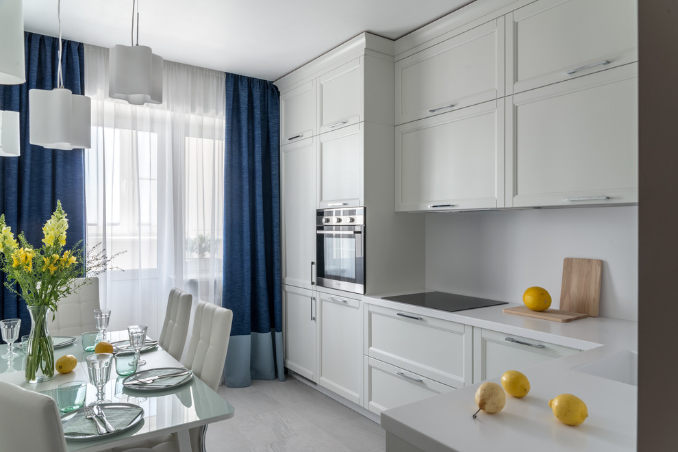 Photo of a contemporary l-shaped separate kitchen in Moscow with an undermount sink, shaker cabinets, white cabinets, white splashback, stainless steel appliances, no island, grey floor and white benchtop.