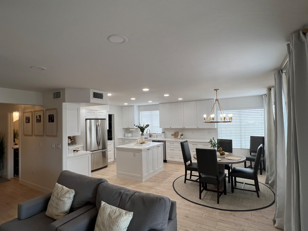 Eat-in kitchen - mid-sized transitional open concept laminate floor eat-in kitchen idea in Phoenix with white walls, an undermount sink, shaker cabinets, white cabinets, solid surface countertops, white backsplash, subway tile backsplash, stainless steel appliances, an island and white countertops