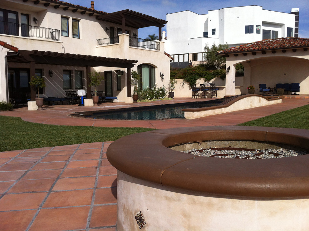 Photo of a mid-sized mediterranean backyard full sun garden in Orange County with a fire feature and natural stone pavers.