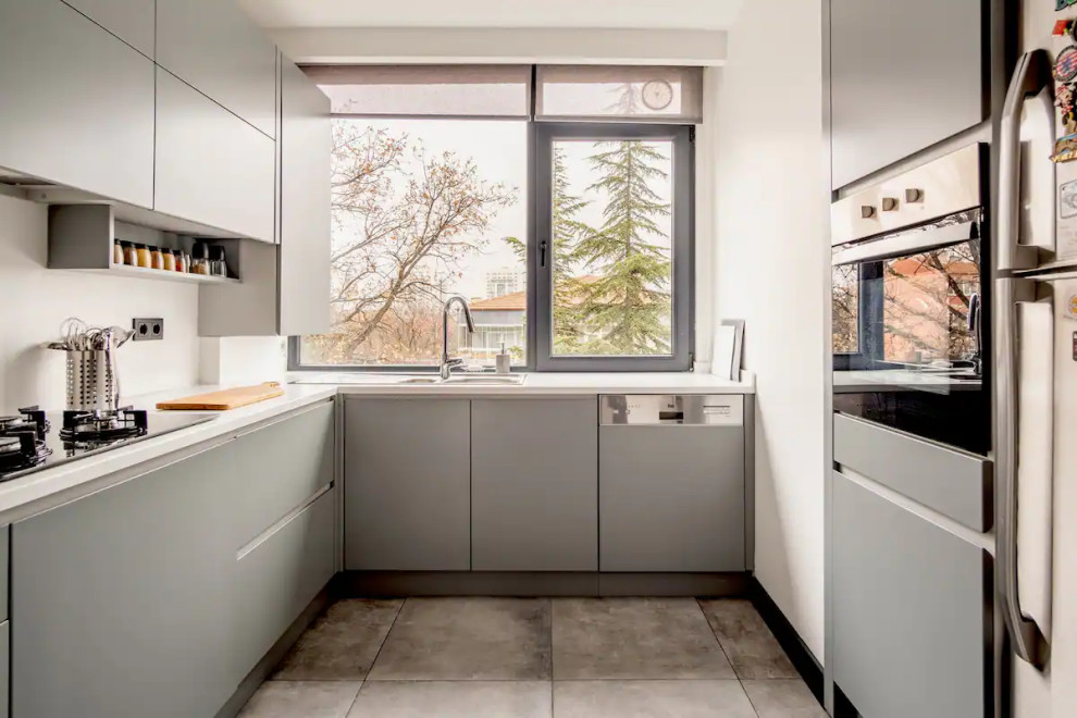 Small modern l-shaped enclosed kitchen in London with a double-bowl sink, flat-panel cabinets, grey cabinets, engineered stone countertops, ceramic flooring, no island, grey floors and white worktops.
