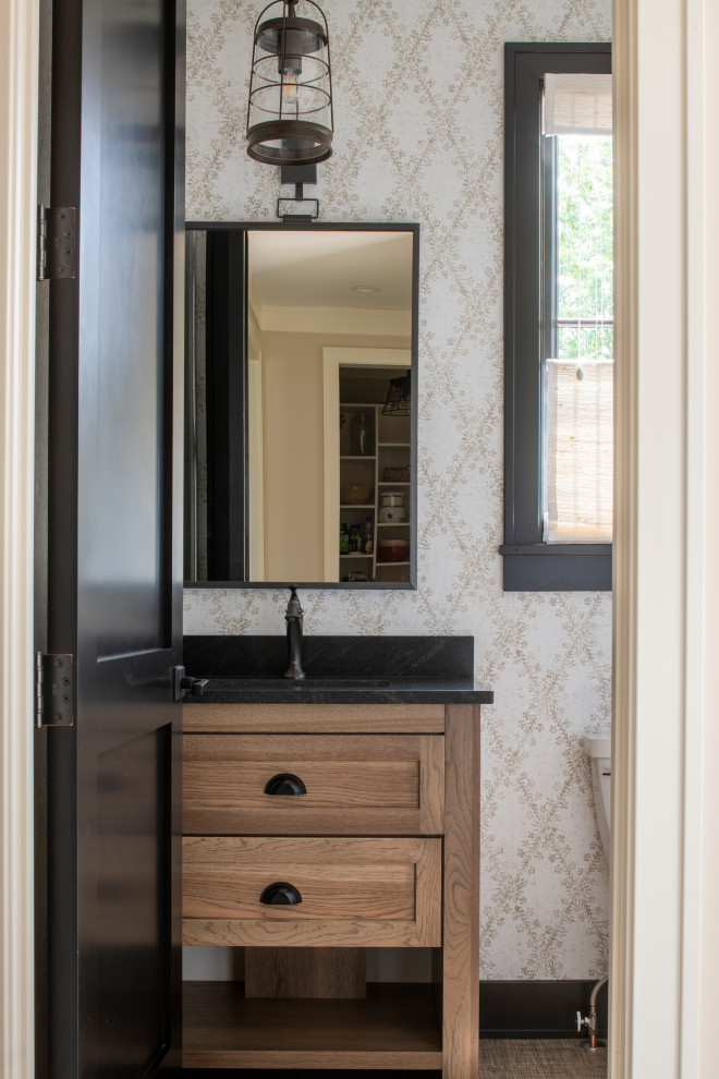 Inspiration for a small country cloakroom in Minneapolis with recessed-panel cabinets, medium wood cabinets, a one-piece toilet, black tiles, vinyl flooring, a submerged sink, granite worktops, multi-coloured floors, black worktops, a built in vanity unit and wallpapered walls.