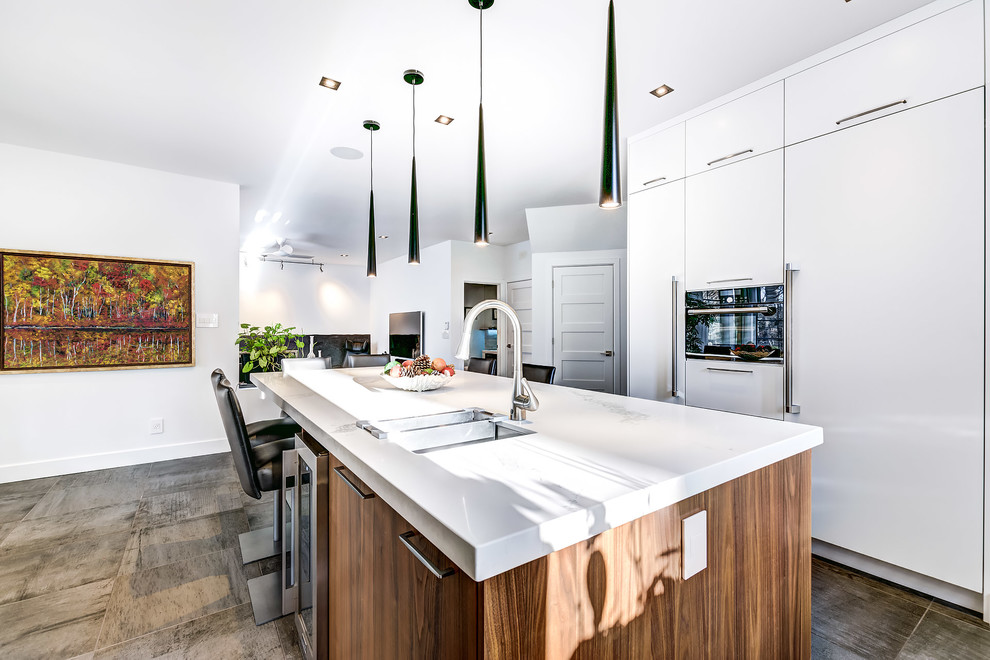Inspiration for a mid-sized contemporary u-shaped eat-in kitchen in Montreal with an undermount sink, flat-panel cabinets, white cabinets, quartz benchtops, white splashback, cement tile splashback, panelled appliances, ceramic floors, with island and brown floor.