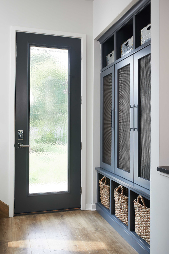 This is an example of a mid-sized contemporary mudroom in Grand Rapids with white walls, light hardwood floors, a single front door, a dark wood front door and brown floor.