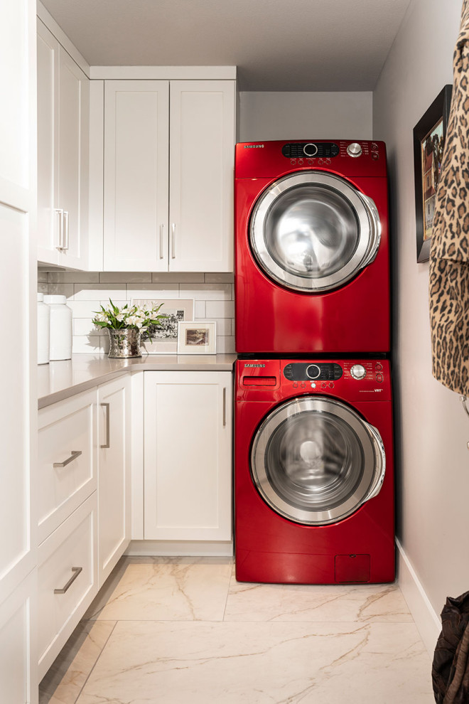 Immagine di una piccola lavanderia multiuso moderna con ante bianche, top in quarzite, pavimento in gres porcellanato, lavatrice e asciugatrice a colonna e top grigio