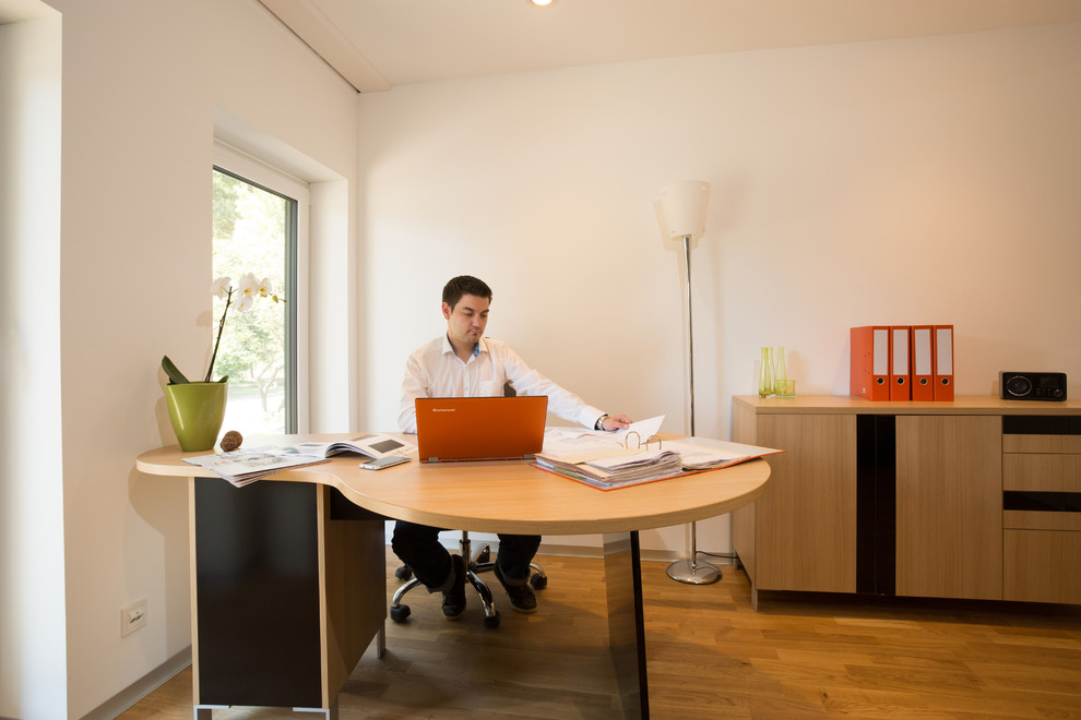 Esempio di un ampio ufficio minimal con pareti bianche, pavimento in legno verniciato e scrivania autoportante