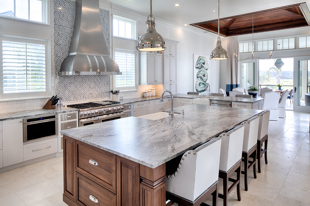 Design ideas for a beach style eat-in kitchen in Atlanta with a farmhouse sink, recessed-panel cabinets, white cabinets, multi-coloured splashback, stainless steel appliances, with island, beige floor and grey benchtop.