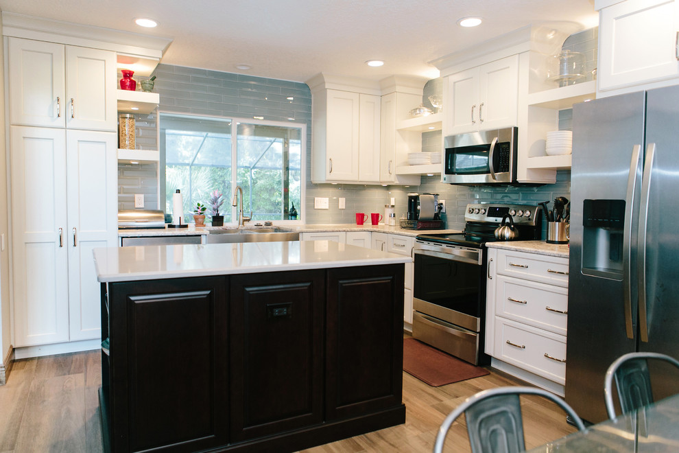 Design ideas for a mid-sized transitional eat-in kitchen in Orlando with a farmhouse sink, recessed-panel cabinets, white cabinets, grey splashback, subway tile splashback, stainless steel appliances, with island, granite benchtops and porcelain floors.