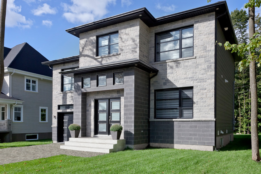 Mid-sized contemporary two-storey grey house exterior in Other with stone veneer and a flat roof.