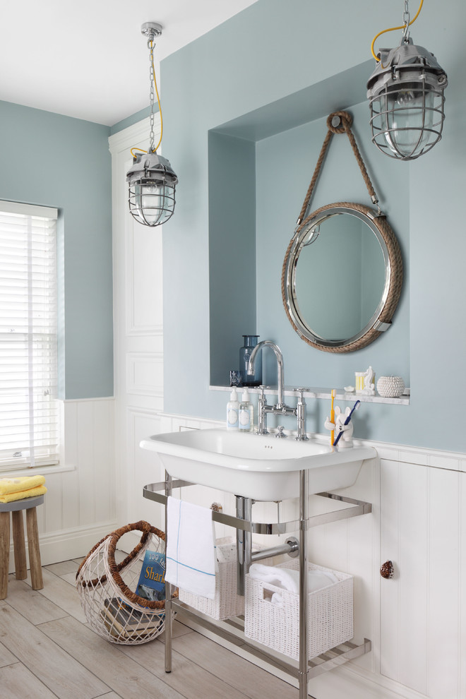 Design ideas for a small beach style master bathroom in London with blue walls, light hardwood floors and a console sink.
