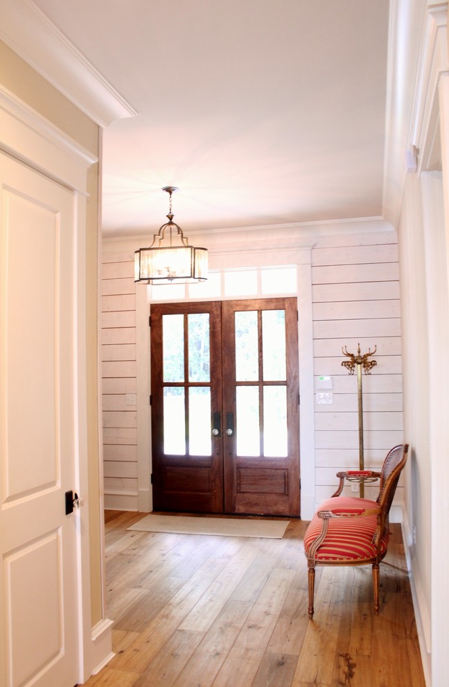 Design ideas for a foyer in Other with white walls, light hardwood floors, a double front door and a dark wood front door.