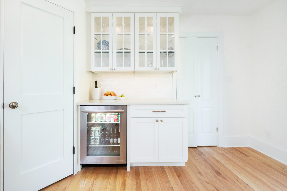 Exempel på ett stort klassiskt vit vitt kök, med en undermonterad diskho, skåp i shakerstil, vita skåp, bänkskiva i kvarts, vitt stänkskydd, stänkskydd i keramik, rostfria vitvaror, ljust trägolv, en köksö och brunt golv