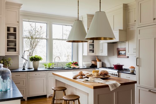 Bright, traditional kitchen with off-white kitchen cabinet units, a wood-top island, and dark countertops
