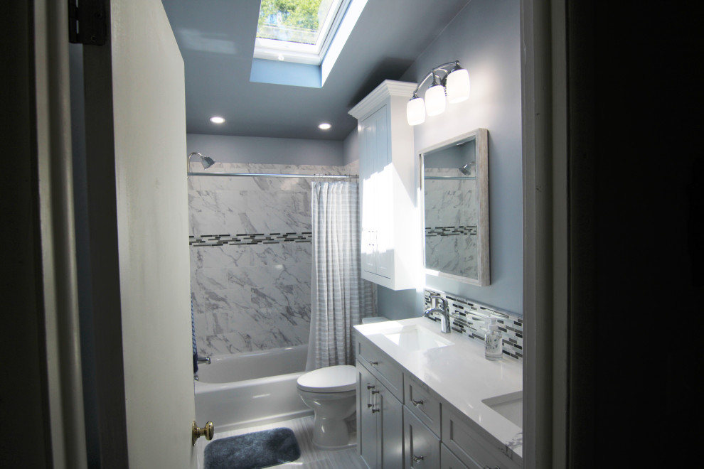 Photo of a mid-sized traditional master bathroom in Baltimore with recessed-panel cabinets, white cabinets, an alcove tub, a shower/bathtub combo, a two-piece toilet, black and white tile, ceramic tile, blue walls, ceramic floors, an undermount sink, granite benchtops, grey floor, a shower curtain, white benchtops, a double vanity, a built-in vanity and vaulted.