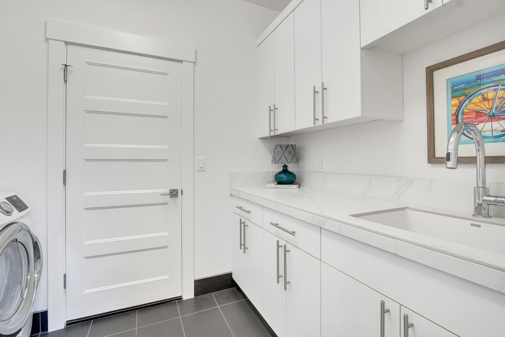 Photo of a mid-sized contemporary galley dedicated laundry room in Portland with a drop-in sink, flat-panel cabinets, white cabinets, tile benchtops and white walls.