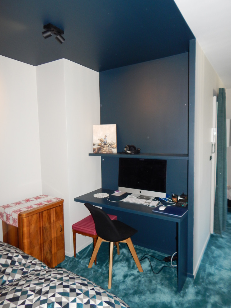 Photo of a small midcentury home office in Lyon with blue walls, carpet, a built-in desk and blue floor.