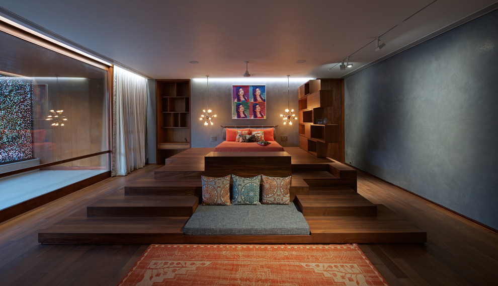 Expansive contemporary bedroom in Ahmedabad with grey walls and dark hardwood floors.