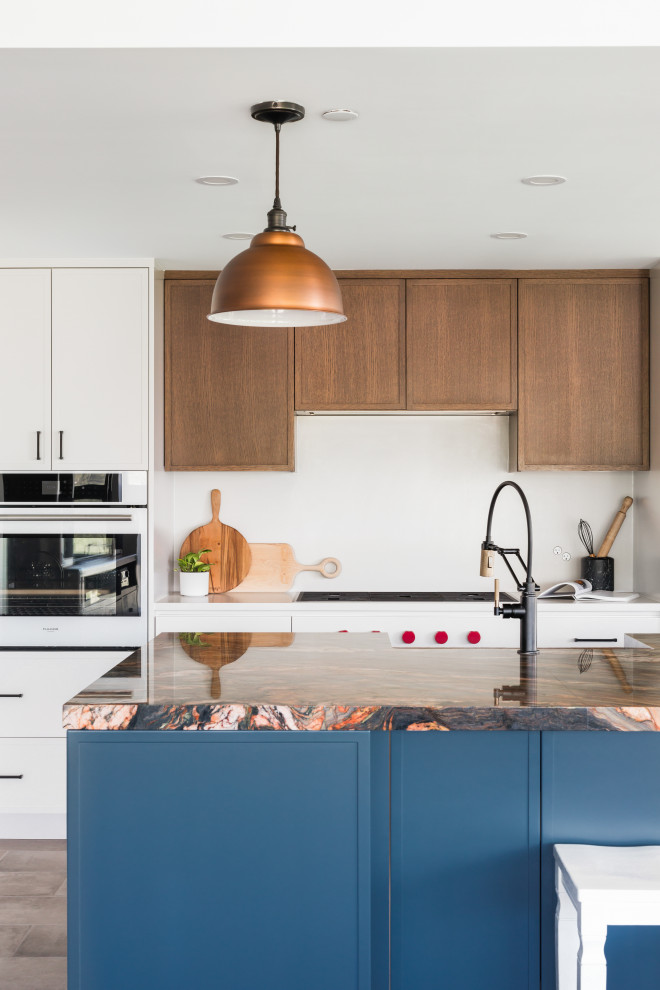 This is an example of a medium sized classic single-wall kitchen/diner in Vancouver with a double-bowl sink, shaker cabinets, white cabinets, quartz worktops, white splashback, engineered quartz splashback, white appliances, light hardwood flooring, an island, beige floors and white worktops.