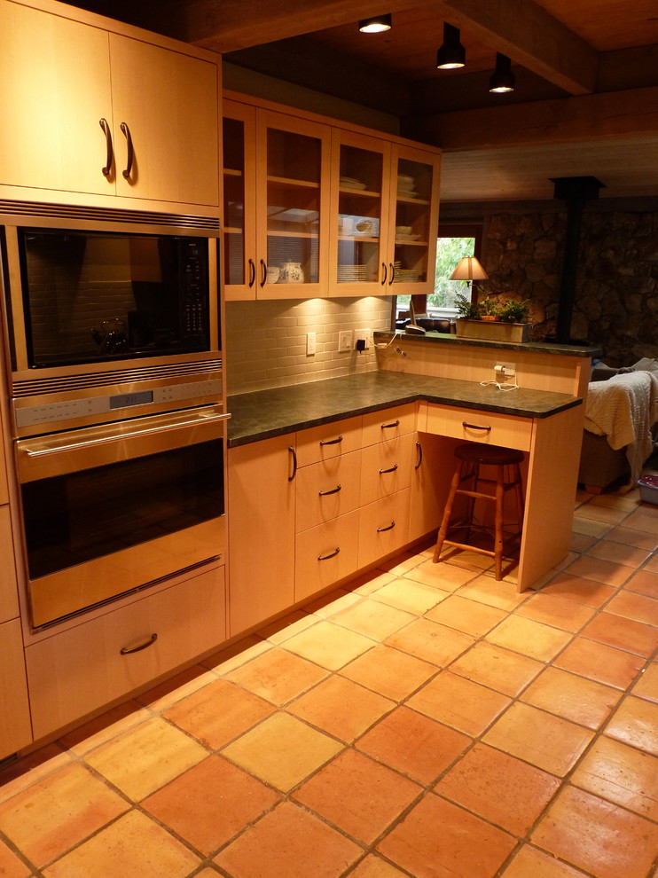 Example of a transitional galley eat-in kitchen design in Seattle with an undermount sink, flat-panel cabinets, light wood cabinets, soapstone countertops, gray backsplash, porcelain backsplash and paneled appliances