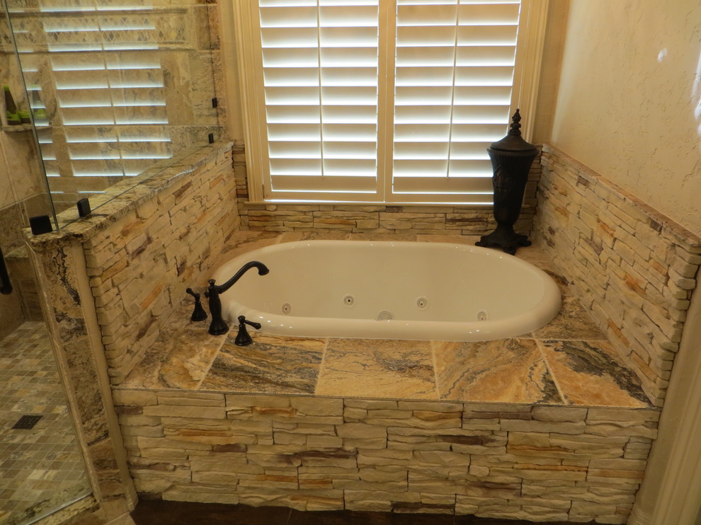 Inspiration for a large country master bathroom in Dallas with an undermount sink, raised-panel cabinets, dark wood cabinets, granite benchtops, a drop-in tub, a corner shower, a two-piece toilet, brown tile, stone tile, beige walls and ceramic floors.
