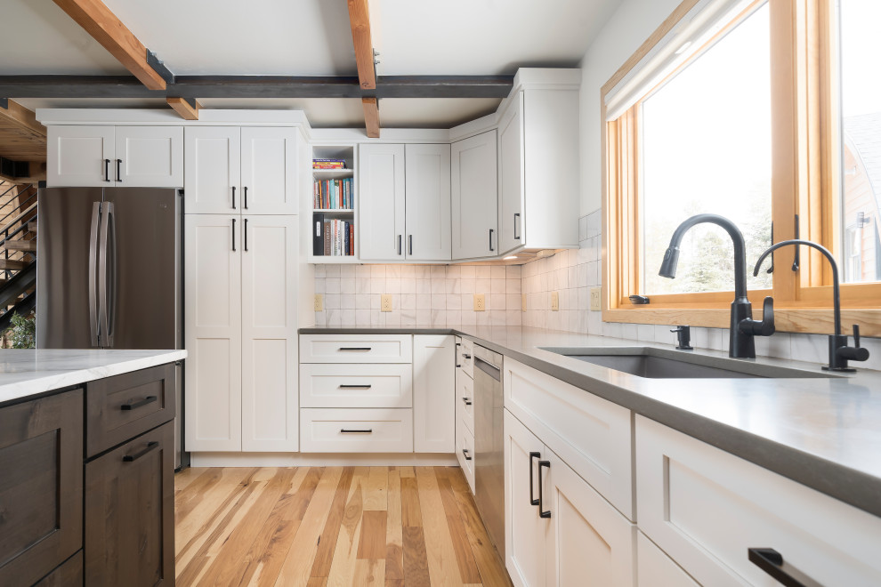 Mid-sized contemporary l-shaped kitchen in Denver with shaker cabinets, white cabinets, stainless steel appliances, medium hardwood floors, with island, brown floor and exposed beam.