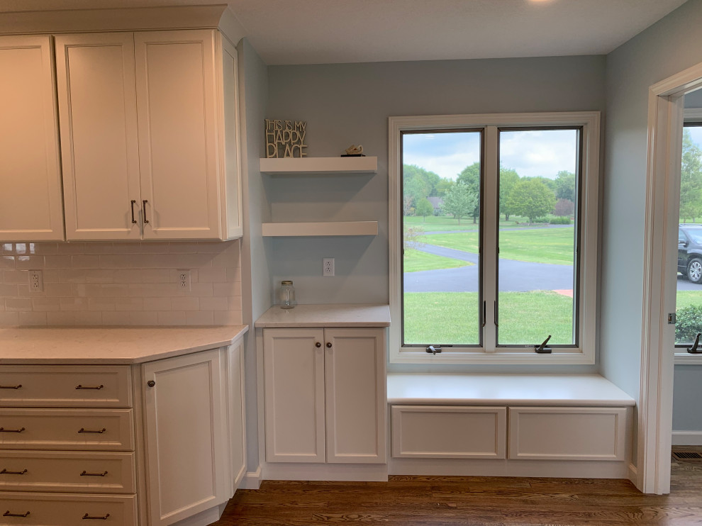 Large transitional u-shaped medium tone wood floor and brown floor open concept kitchen photo with an undermount sink, recessed-panel cabinets, white cabinets, quartz countertops, white backsplash, stainless steel appliances, an island and white countertops