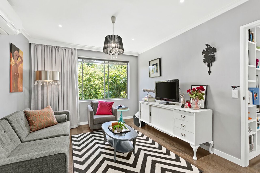 Photo of a small transitional open concept living room in Melbourne with grey walls, medium hardwood floors and a freestanding tv.