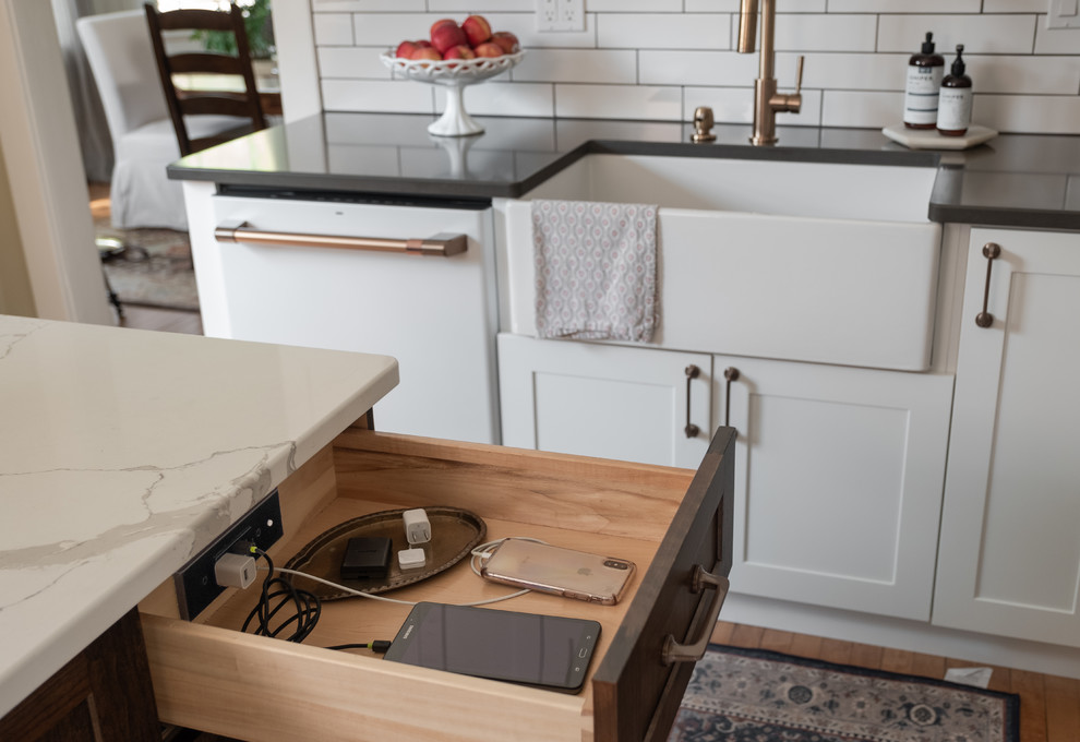 Design ideas for a mid-sized traditional l-shaped eat-in kitchen in Other with a farmhouse sink, shaker cabinets, white cabinets, quartz benchtops, white splashback, ceramic splashback, white appliances, light hardwood floors, with island and grey benchtop.