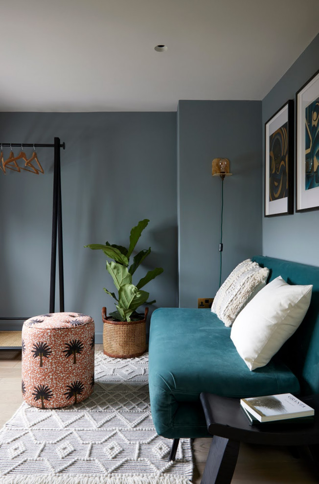 Diseño de despacho minimalista pequeño con paredes azules, suelo de madera clara, escritorio empotrado y suelo beige