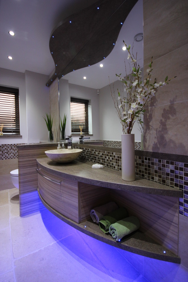 Photo of a small contemporary powder room in Other with a vessel sink, flat-panel cabinets, medium wood cabinets, solid surface benchtops, a wall-mount toilet, multi-coloured tile, mosaic tile and travertine floors.