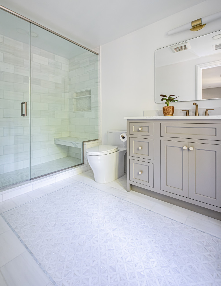 Пример оригинального дизайна: ванная комната среднего размера в классическом стиле с фасадами в стиле шейкер, серыми фасадами, унитазом-моноблоком, белыми стенами, мраморным полом, врезной раковиной, столешницей из искусственного кварца, белым полом, душем с распашными дверями, белой столешницей, сиденьем для душа, тумбой под одну раковину и встроенной тумбой