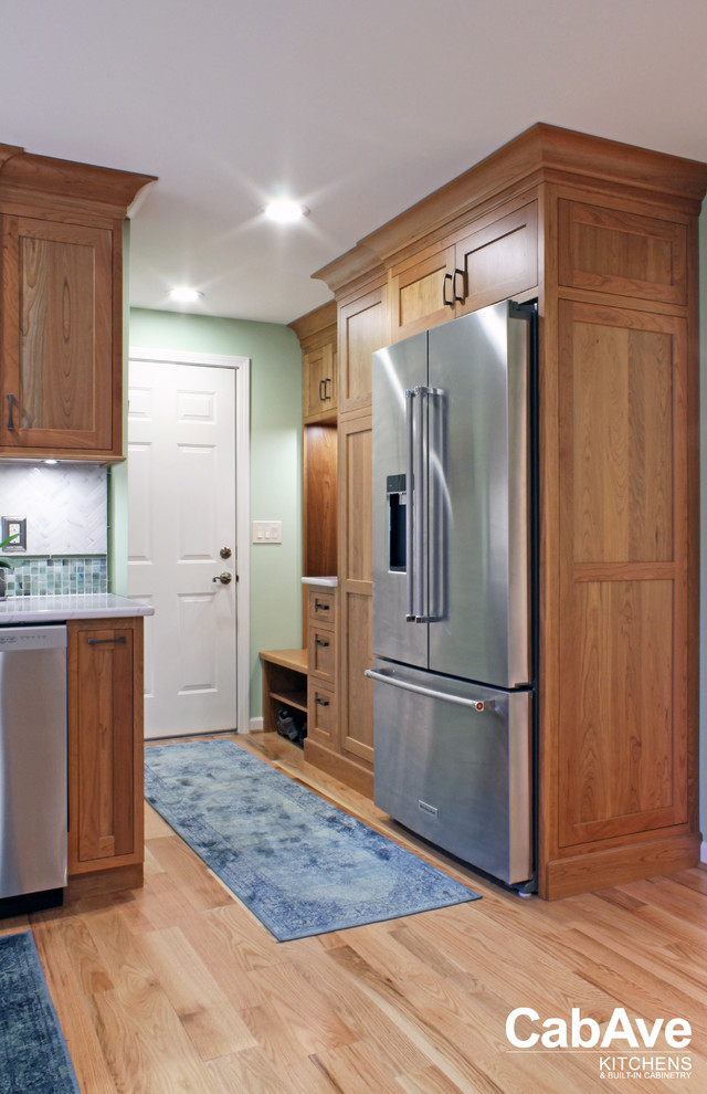Large transitional u-shaped light wood floor and beige floor open concept kitchen photo with an undermount sink, recessed-panel cabinets, light wood cabinets, quartz countertops, green backsplash, mosaic tile backsplash, stainless steel appliances and a peninsula