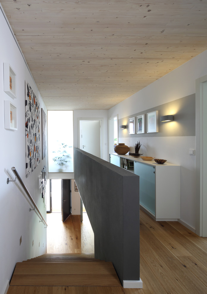 Photo of a mid-sized contemporary hallway in Munich with white walls, light hardwood floors and beige floor.