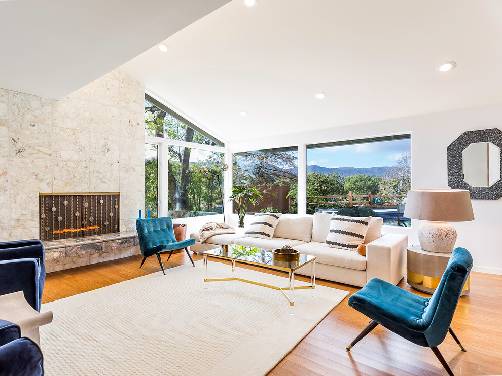 Photo of a mid-sized midcentury formal open concept living room in Los Angeles with white walls, medium hardwood floors, no tv, a standard fireplace and a stone fireplace surround.