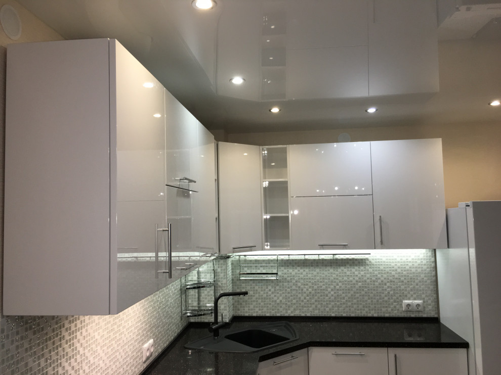 Medium sized contemporary grey and white u-shaped open plan kitchen in Other with a submerged sink, flat-panel cabinets, white cabinets, composite countertops, grey splashback, glass tiled splashback, stainless steel appliances, ceramic flooring, no island, beige floors, black worktops and a coffered ceiling.
