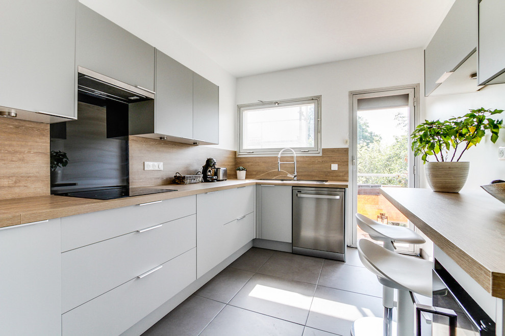 Aménagement d'une grande cuisine scandinave en L fermée avec un évier 1 bac, un placard à porte affleurante, des portes de placard grises, un plan de travail en stratifié, une crédence beige, un électroménager noir, un sol en carrelage de céramique, aucun îlot, un sol gris et un plan de travail beige.