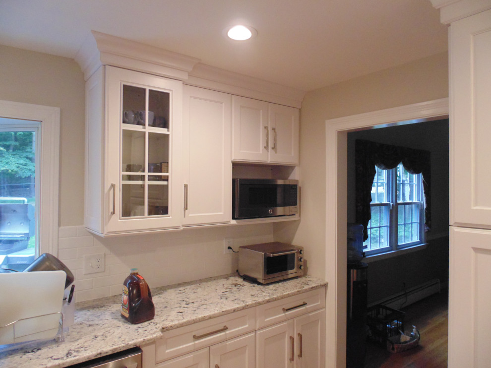 Mid-sized transitional medium tone wood floor and brown floor eat-in kitchen photo with an undermount sink, recessed-panel cabinets, white cabinets, granite countertops, white backsplash, subway tile backsplash, stainless steel appliances, no island and white countertops
