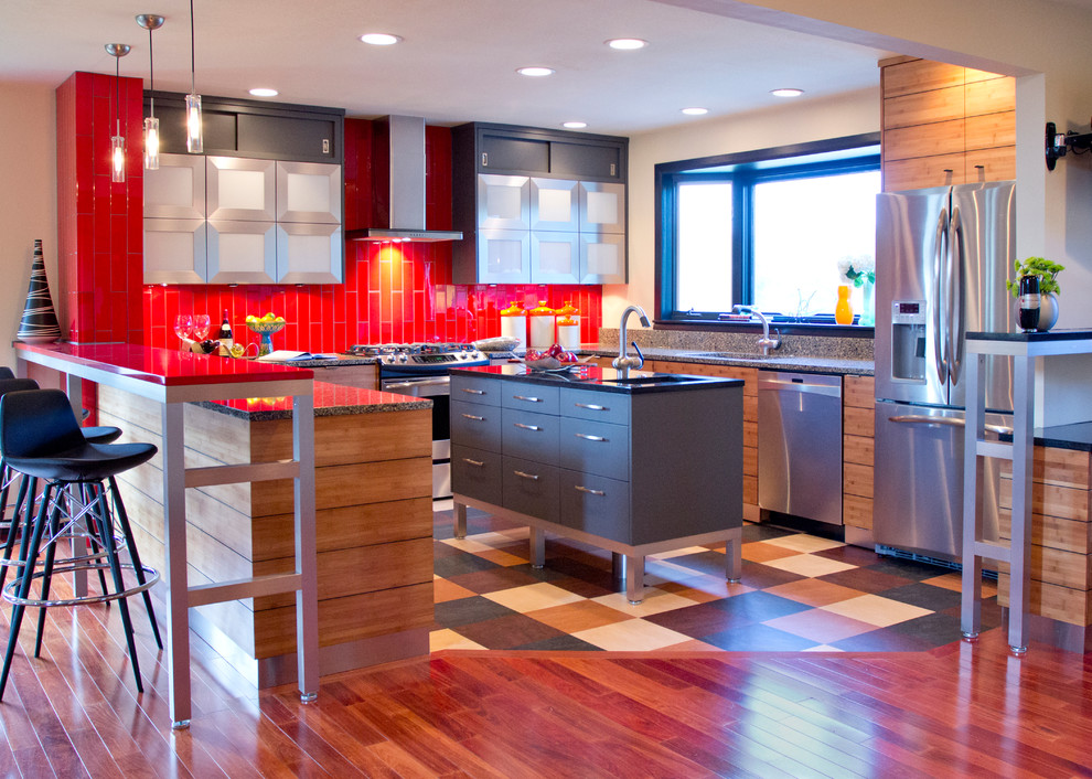 This is an example of a contemporary u-shaped eat-in kitchen in Kansas City with stainless steel appliances, flat-panel cabinets, medium wood cabinets, red splashback, an undermount sink, quartz benchtops, glass tile splashback and red benchtop.