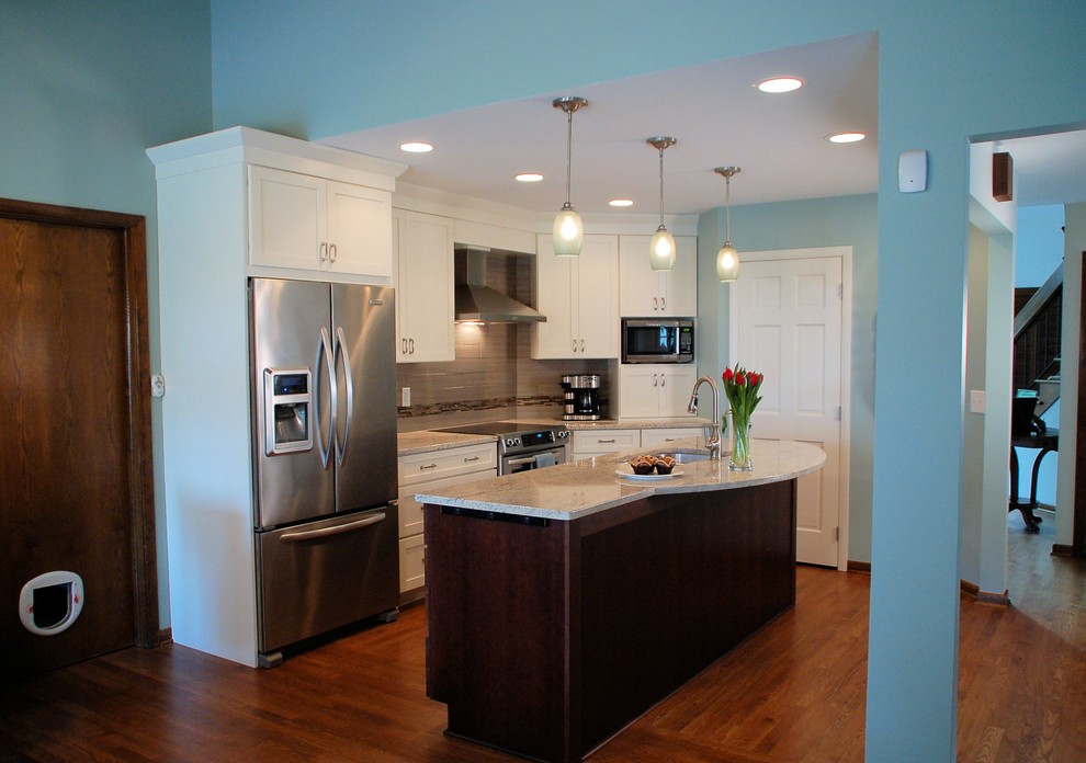 Example of a small transitional single-wall medium tone wood floor eat-in kitchen design in Columbus with an undermount sink, shaker cabinets, white cabinets, granite countertops, gray backsplash, ceramic backsplash, stainless steel appliances and an island