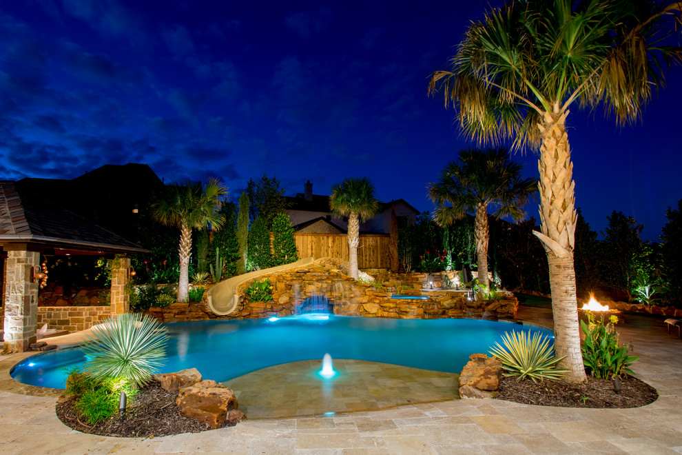 Inspiration for a mid-sized tropical backyard custom-shaped pool in Dallas with a water slide and natural stone pavers.